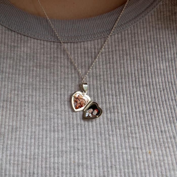 Model wearing large silver heart-shaped locket open with photos inside