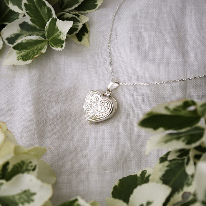 Heart shaped photo locket necklace with embellishment on white linen