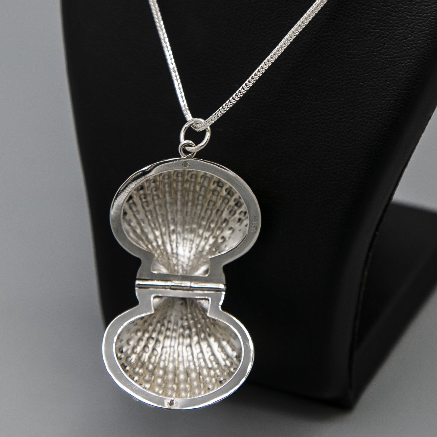 sterling silver clam shell-shaped photo locket pendant on thick silver italian chain displayed on black bust. Photo locket pendant is open showing locket photo insert.