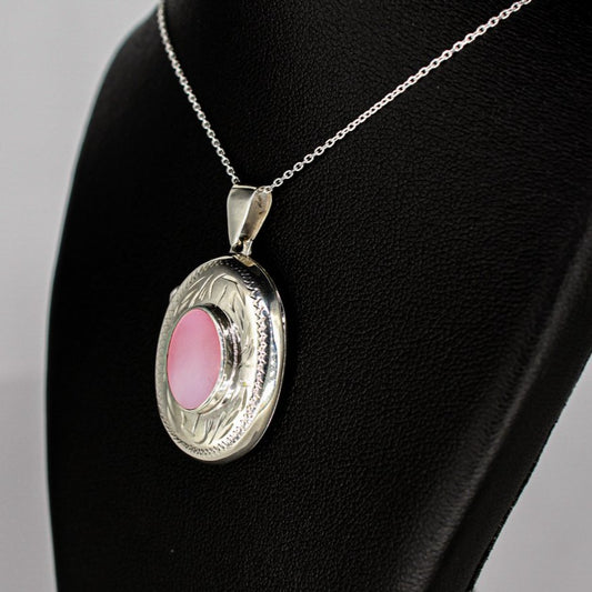 silver locket oval shaped with pink mother of pearl inset on a silver chain