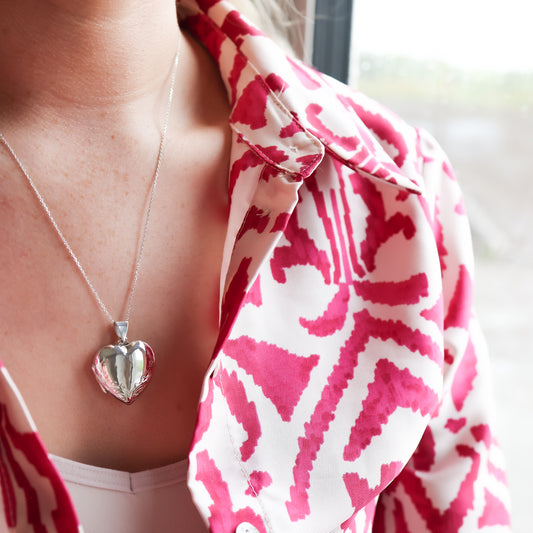 large heart shaped locket necklace worn by model wearing pink and white shirt