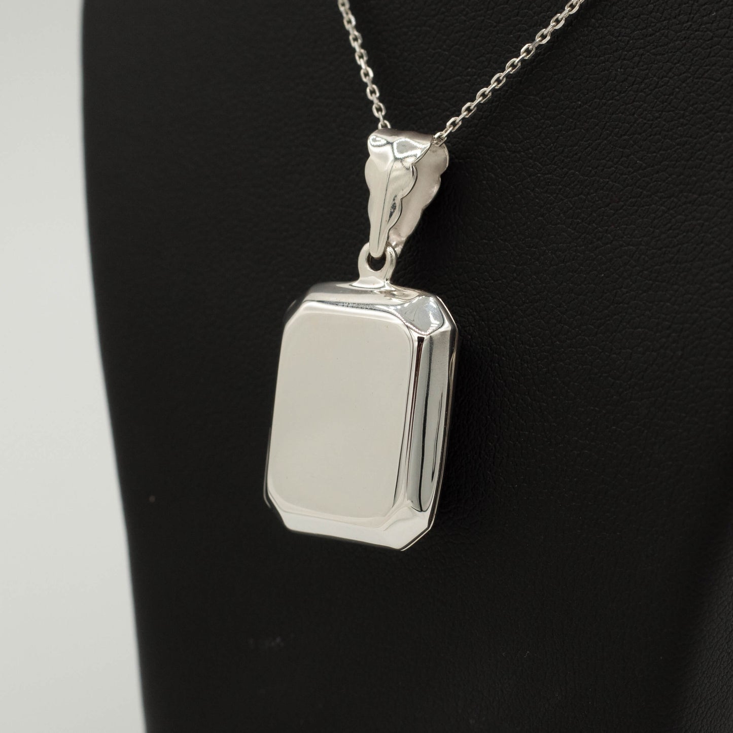 Close up of rectangle shaped locket on a black bust