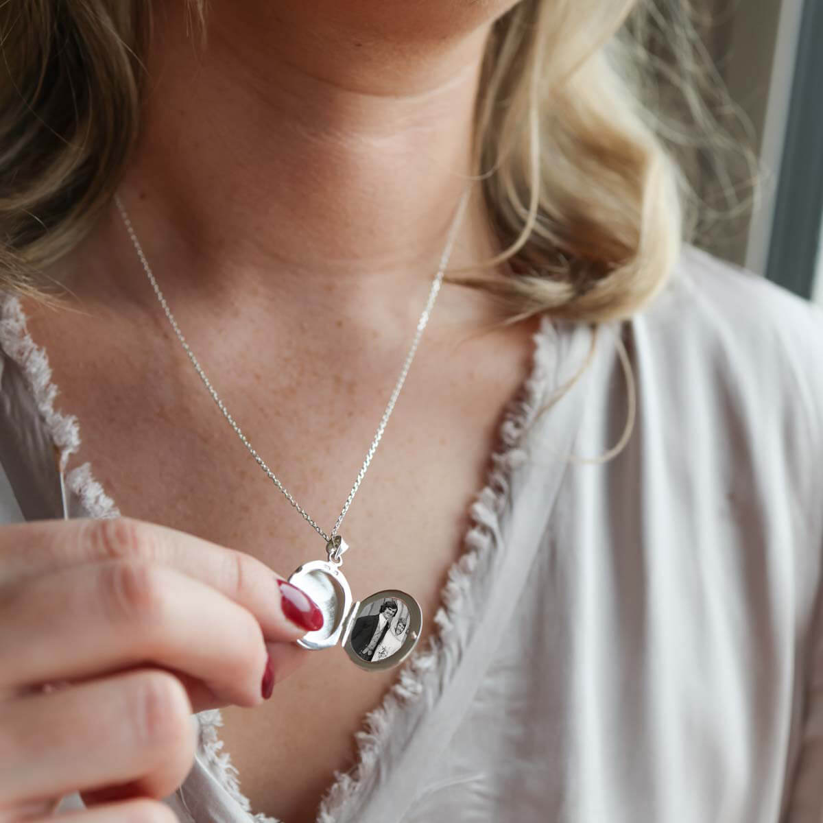 Model holding open oval picture locket necklace