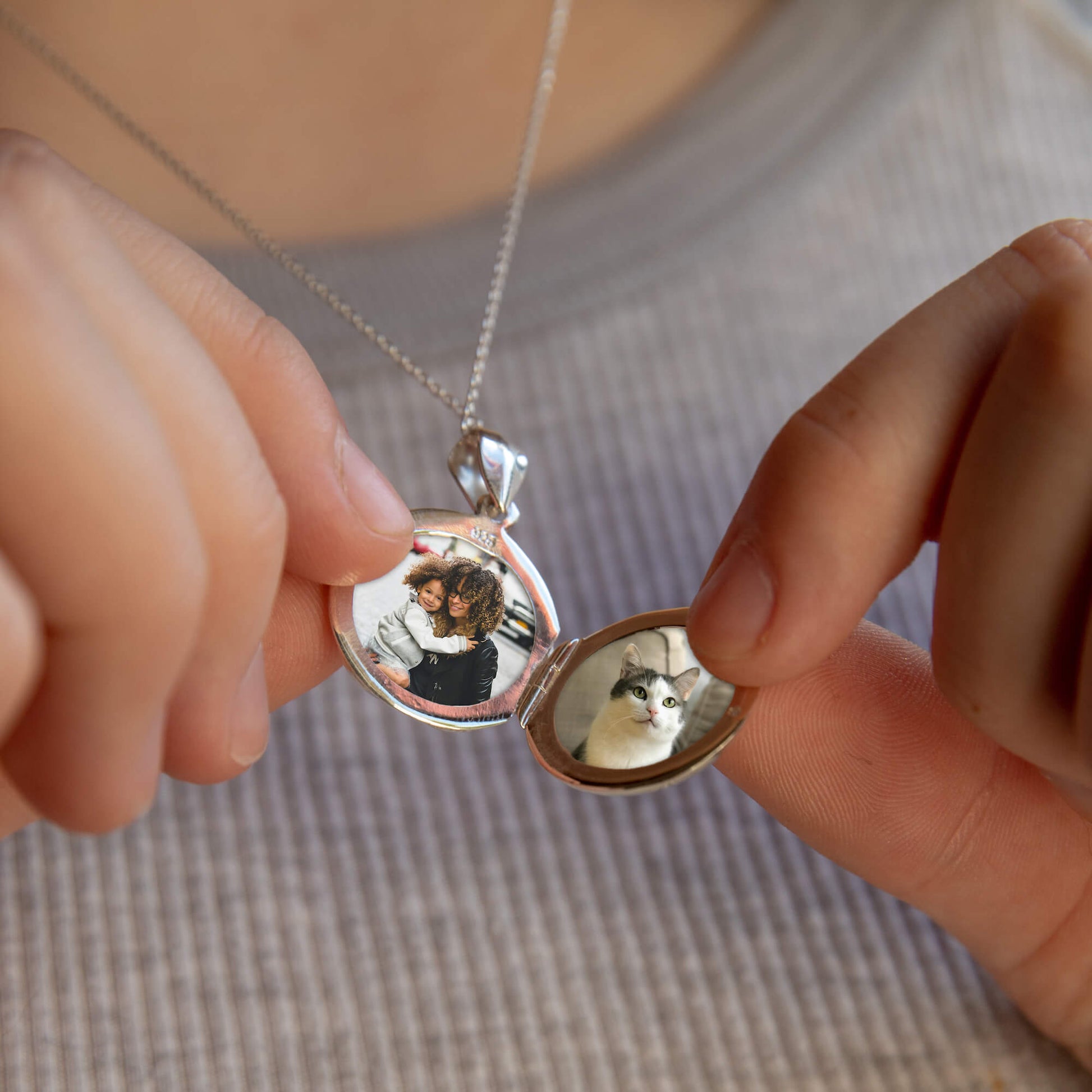 model holding open a large silver locket to reveal two photos