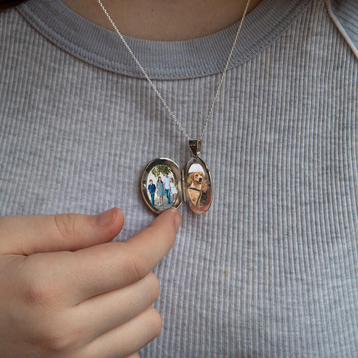 Model wearing large oval locket which is open showing photos