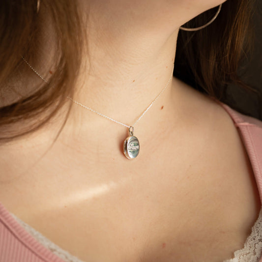 Necklace with a pendant worn by a person, focusing on the necklace and skin.
