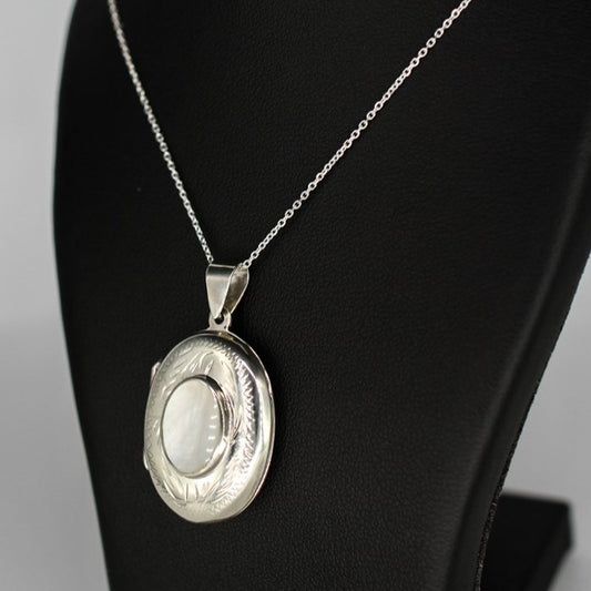 Oval shaped embellished silver photo locket necklace with white mother of pearl inlay on Italian silver chain displayed on black bust.