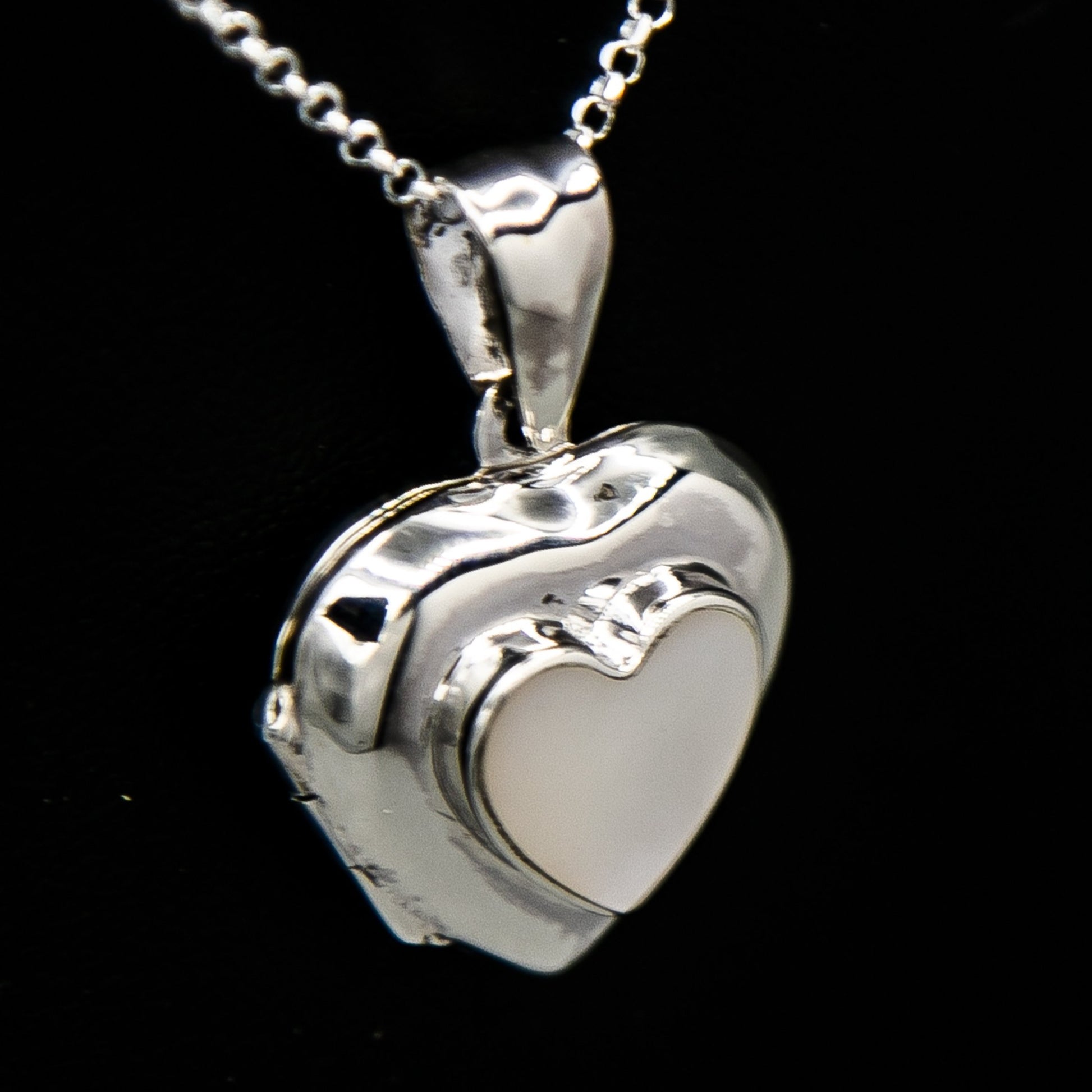 Silver heart shaped photo locket pendant with white mother of pearl inset with a silver Italian chain displayed on a black bust.